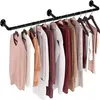 A black metal garment rack mounted on a white wall, displaying several hanging clothes. Produktbild-Vorschau