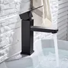 A black faucet is installed on a white sink, with water flowing into the sink. Podgląd zdjęcia produktu