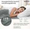 A woman sleeping peacefully on a bed with a gray fitted sheet and white pillow. The image highlights comfort and breathability. Produktbild-Vorschau