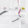 A close-up view of a sheer curtain with floral patterns and a violet stripe, layered over text. Produktbild-Vorschau