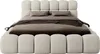 A beige upholstered bed with a headboard and mattress, shown from the front. Produktbild-Vorschau
