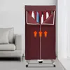 A burgundy electric clothes dryer stand with clothes hanging inside, placed next to a light gray sofa in a room with a window. Podgląd zdjęcia produktu