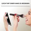 A woman is applying makeup using a mirror and a brush. Produktbild-Vorschau