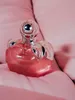 A pink perfume bottle with silver accents rests on a pink fabric surface. Anteprima dell’immagine prodotto