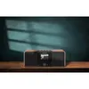 A digital radio with a wooden finish is placed on a wooden table in front of a teal wall with shadows. Náhľad obrázku produktu