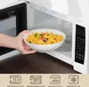 A hand places a bowl of pasta into a microwave. Produktbild-Vorschau