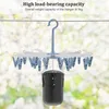 A blue and white sock drying rack with 20 clips is shown hanging from a wire, with a black weighted bag attached to the center. The background is a blurred outdoor scene with greenery and light. Produktbild-Vorschau