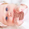 A close-up shot of a baby's face with a teething toy in its mouth. Voir les images du produit