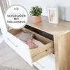 A close-up view of an open drawer in a dresser, showing baby items inside, with a plant and picture frame on top of the dresser. Anteprima dell’immagine prodotto