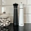 Two spice grinders and a decorative jar on a countertop with a tiled backsplash. Produktbild-Vorschau
