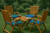 A wooden table and chairs set with blue cushions on a grassy lawn. Produktbild-Vorschau
