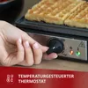 A hand is adjusting the temperature dial on a waffle maker with waffles inside. Produktbild-Vorschau