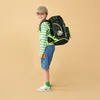 A young boy wearing a backpack and a cap, posing for a photo. Náhled obrázku produktu