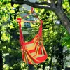 A colorful striped hammock chair hanging from a tree branch in a garden setting. Produktbild-Vorschau