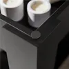 A close-up view of the corner of a black coffee table, showing a small circular felt pad attached to the underside of the corner. Produktbild-Vorschau