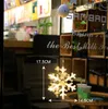 A snowflake-shaped LED light hanging in a window, with measurements indicated. Produktbild-Vorschau