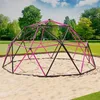 A pink and black geodesic dome climber in a sandy playground area, with a grassy park and trees in the background. Náhled obrázku produktu