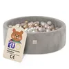 A grey corduroy ball pit filled with pink, gold, and white balls, with a tag attached. Produktbild-Vorschau
