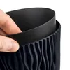 A hand is shown pressing on the rim of a dark gray planter. Podgląd zdjęcia produktu