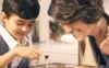 A mother and son playing a board game with an hourglass. Produktbild-Vorschau