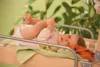 A baby lying on a changing table with a plant in the background. Produktbild-Vorschau
