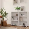 A white bookshelf with items on its shelves, next to a potted plant. Produktbild-Vorschau