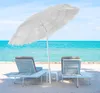 Two lounge chairs and a small table under a large white umbrella on a sandy beach, with the ocean and sky in the background. Produktbild-Vorschau