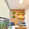 A balcony with a seating area, table, and plants, featuring a beige roller blind. Náhled obrázku produktu