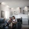 A mother and son are sitting on a couch in a modern living room, looking at a tablet. Produktbild-Vorschau