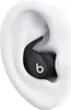 A close-up view of a black Beats by Dr. Dre Powerbeats Fit earbud inserted into a white ear. Produktbild-Vorschau