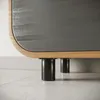 A close-up view of the bottom of a cabinet, showing its black cylindrical legs and the wooden frame with a gray textured surface. Produktbild-Vorschau