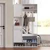 A white entryway organizer with a bench, shelves, hooks, and storage compartments, placed next to a white door. Voir les images du produit