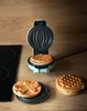 A mini waffle maker with pumpkin-shaped waffles and other waffle shapes on a kitchen counter. Podgląd zdjęcia produktu