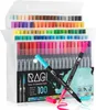 A set of 100 dual-tip marker pens in a clear plastic case, with two pens in the foreground showing their tips and ink trails. Produktbild-Vorschau