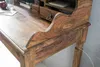A close-up view of a wooden desk with a curved edge and a drawer pull. Produktbild-Vorschau