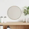 A round mirror with a silver frame is displayed on a wooden shelf, surrounded by cosmetic products and a plant. Náhled obrázku produktu