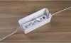 A white cable management box containing a power strip is placed on a wooden surface. Anteprima dell’immagine prodotto