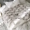 A cozy bed with a patterned blanket and a mug of coffee. Produktbild-Vorschau