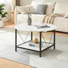 A round coffee table with a marble-look top and a lower shelf is placed in a living room setting, next to a sofa. Podgląd zdjęcia produktu