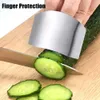A hand wearing a finger guard is slicing a cucumber on a wooden cutting board. Produktbild-Vorschau