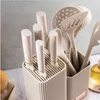 A set of kitchen utensils and knives in a holder, with a blurred background. Produktbild-Vorschau