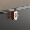 A close-up of a metal bracket with a screw attached to a dark surface, with a textured beige surface in the background. Produktbild-Vorschau