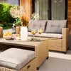 A patio lounge set with a sofa, chairs, and table, set up on a patio with drinks and decorations. Produktbild-Vorschau