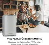 Three young adults are in a kitchen, two are sharing pizza and one is standing next to a mini refrigerator. Produktbild-Vorschau