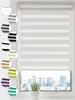 A close-up of a window with a roller blind and a city skyline visible through the window. Produktbild-Vorschau