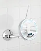 A chrome-finished round mirror with integrated LED lights and a digital clock, mounted on a wall with white tiles. Produktbild-Vorschau