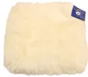 A cream-colored sheepskin seat cushion is shown against a white background. A blue tag with white text and a logo is attached to the upper right corner of the cushion.