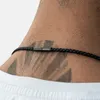 Close-up of a person's neck wearing a black braided leather necklace with a metallic clasp. Podgląd zdjęcia produktu