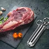 A raw steak with seasoning and a marinade injector on a dark slate. Voir les images du produit