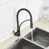 A black kitchen faucet with a flexible hose is shown in use, with water running into a double stainless steel sink. Produktbild-Vorschau